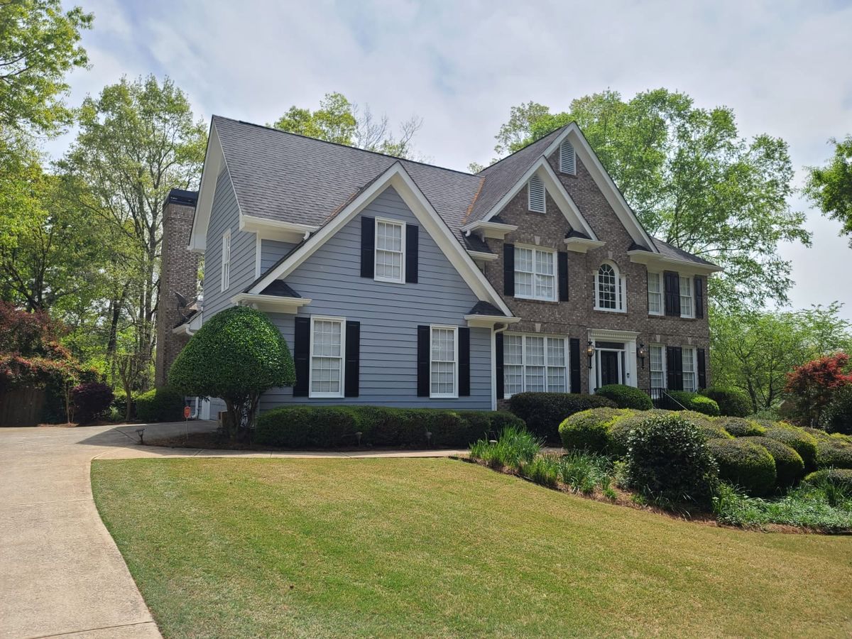 Blue-gray two-story house with black shutters and a brick side