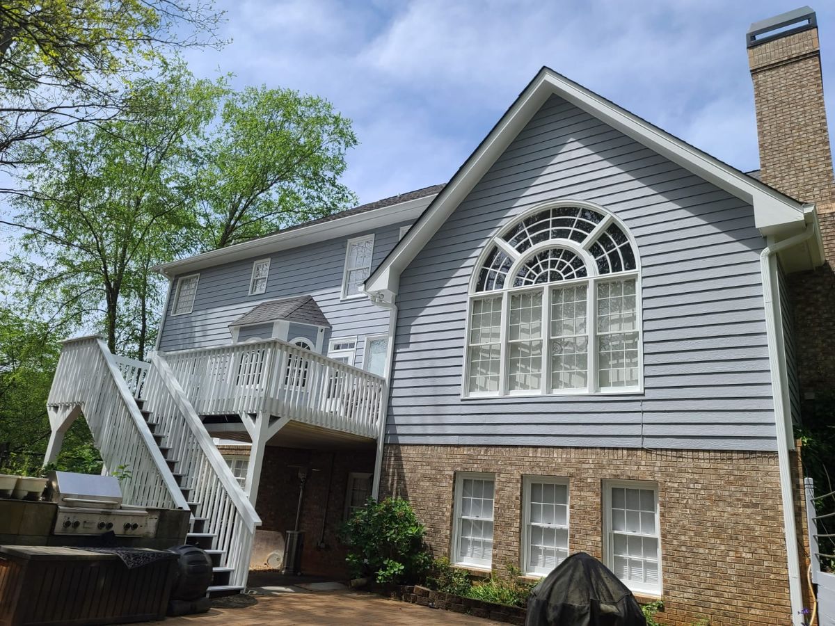 Side of a blue-gray house with a white deck staircase and a large arched window