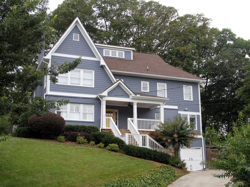 Blue-gray two-story house with white trim and a wraparound porch
