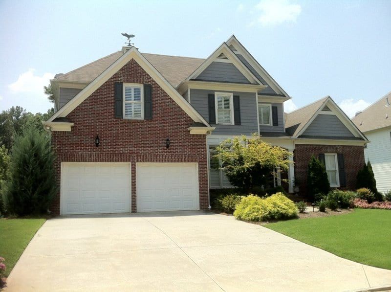 Red brick and gray sided two-story house with a white two-car garage