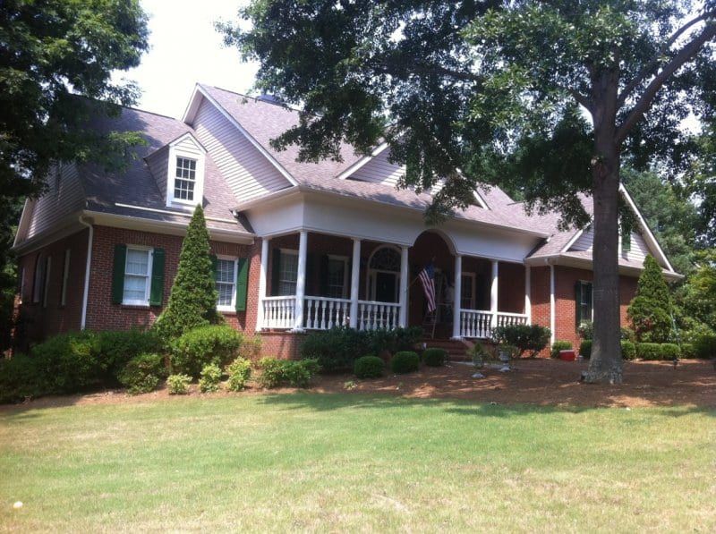Brick house with a white front porch and a pink sided gable