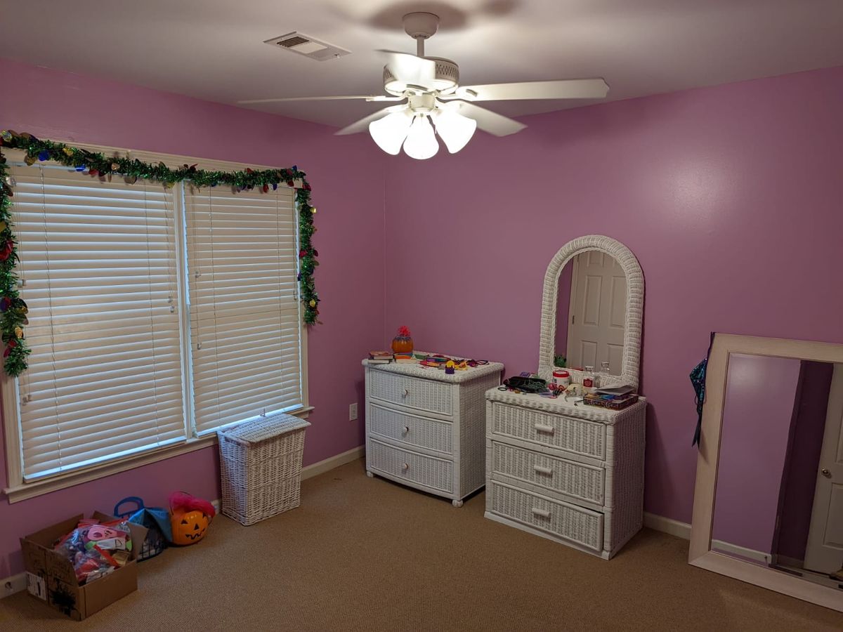 Child's bedroom painted pink, with white furniture and window blinds