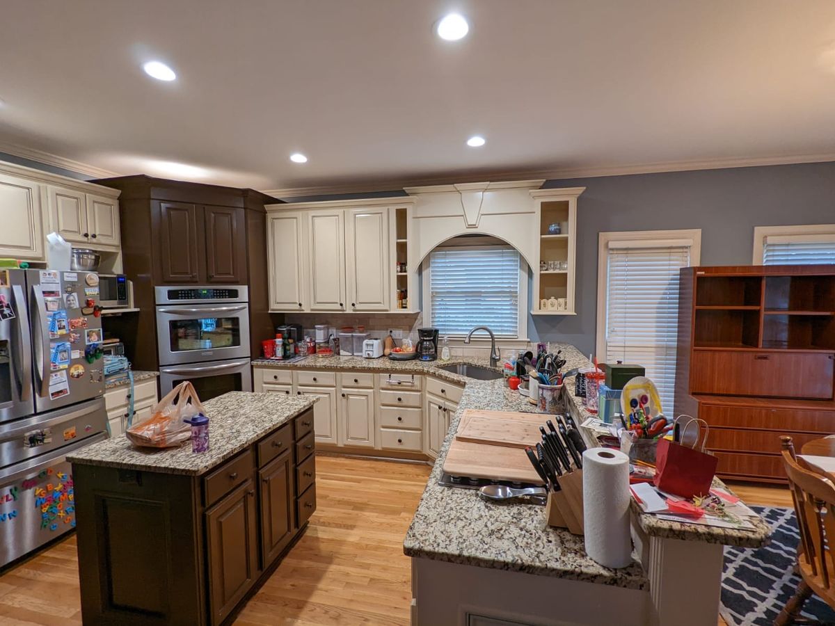 Kitchen with cream cabinets, a dark island, and wood floors