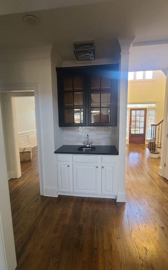 Hallway nook with white lower cabinets and a dark upper cabinet with glass doors
