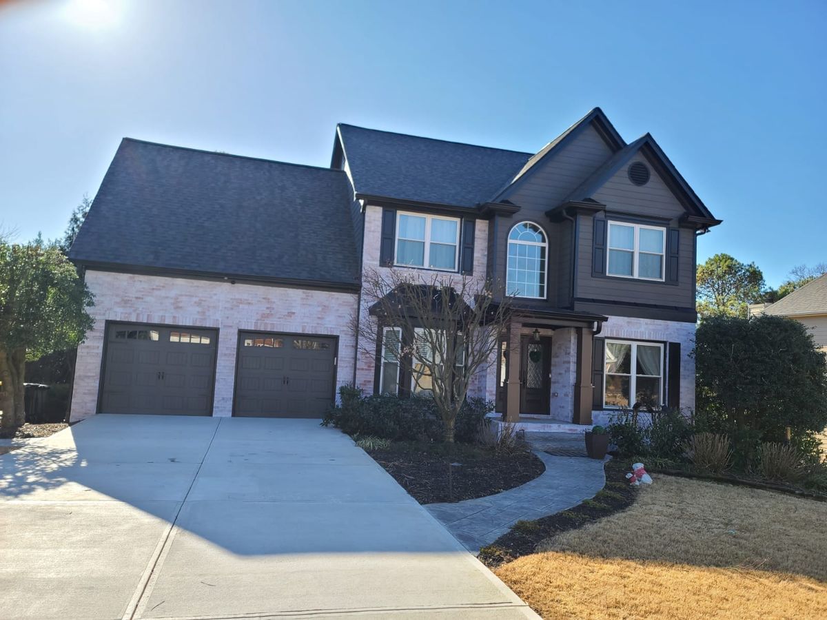 Charcoal gray two-story house with light brick lower walls and dark garage doors
