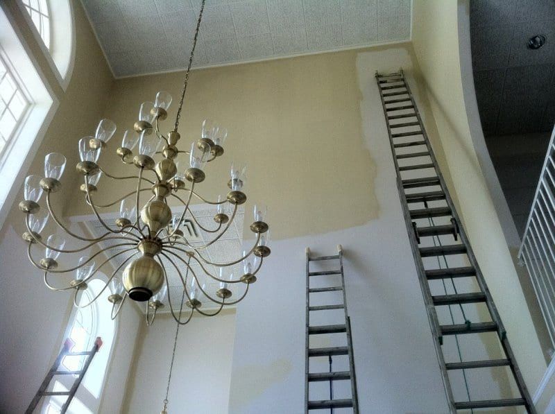 Tall church foyer with a large chandelier and ladders against the walls