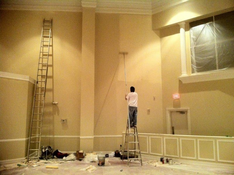 Painter on a ladder painting a column in the sanctuary