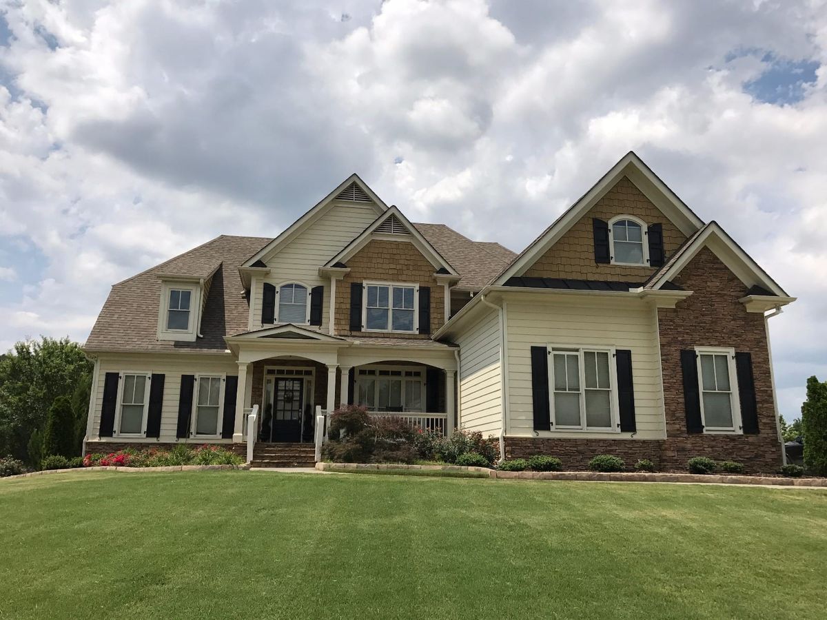 Two-story craftsman house with white siding, black shutters, and stone accents