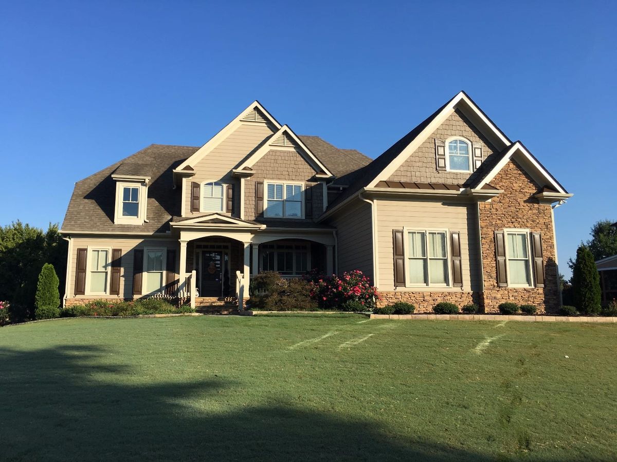 The same house repainted tan, with brown shutters and stone accents
