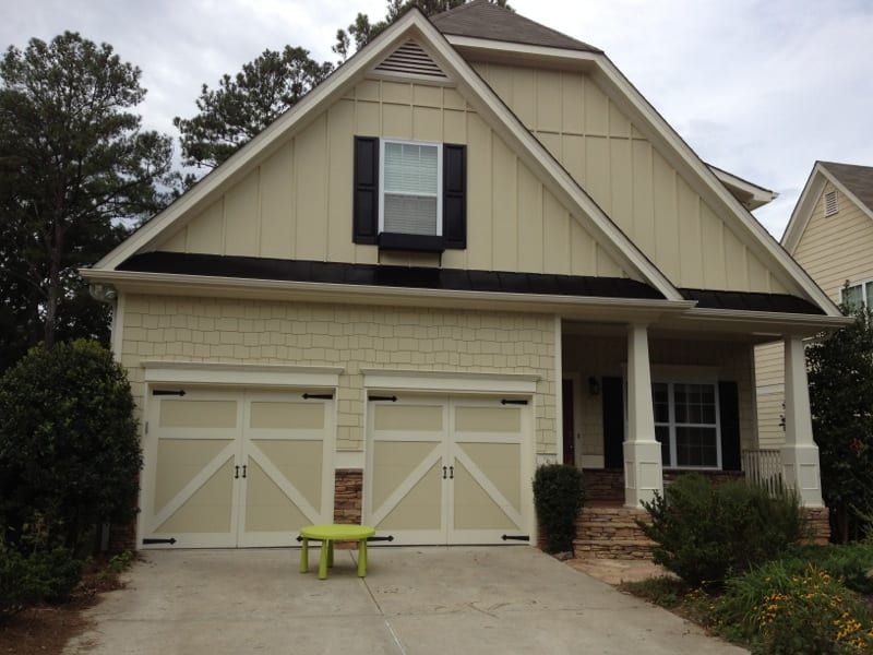 Cream craftsman house with carriage-style garage doors and black shutters