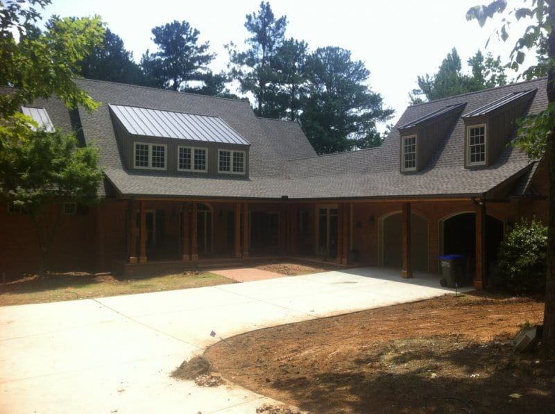 Dark sided house with dormers and a long driveway