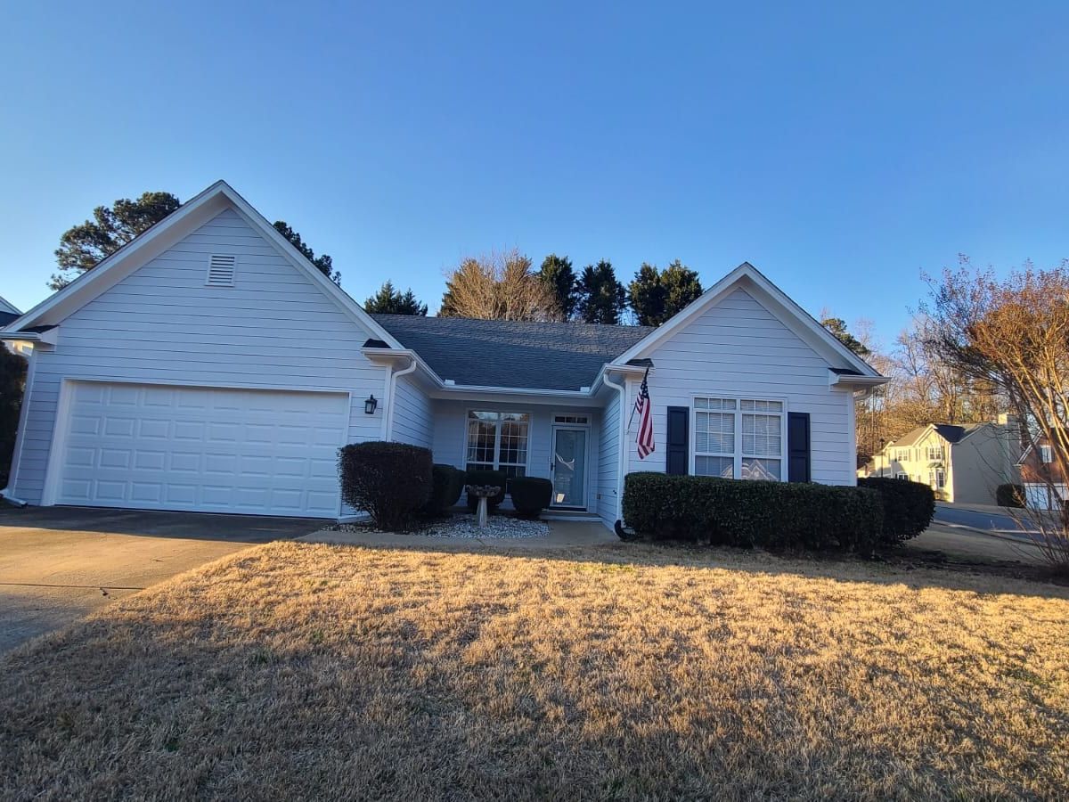 Light gray ranch house with white trim, black shutters, and a two-car garage
