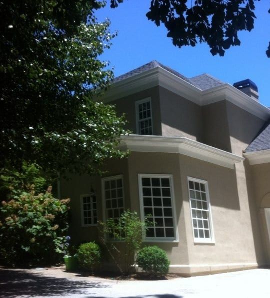 Gray stucco house with white trim and a bay of tall windows