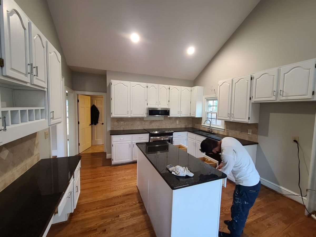 The same kitchen with the cabinets painted white, and a painter finishing the island