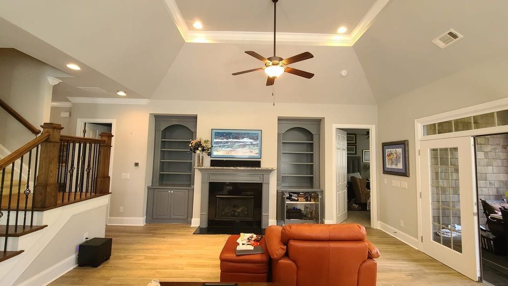 Living room with orange leather chairs, built-in shelves beside a fireplace, and a staircase
