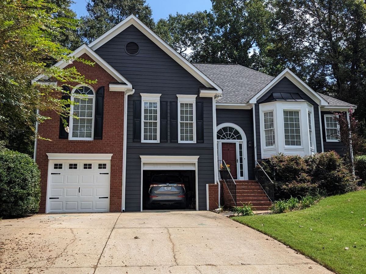 Navy and red brick house with white trim and a white garage door