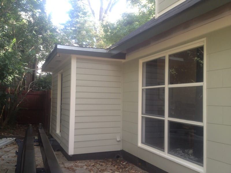 Corner of a house with new tan siding and a large window