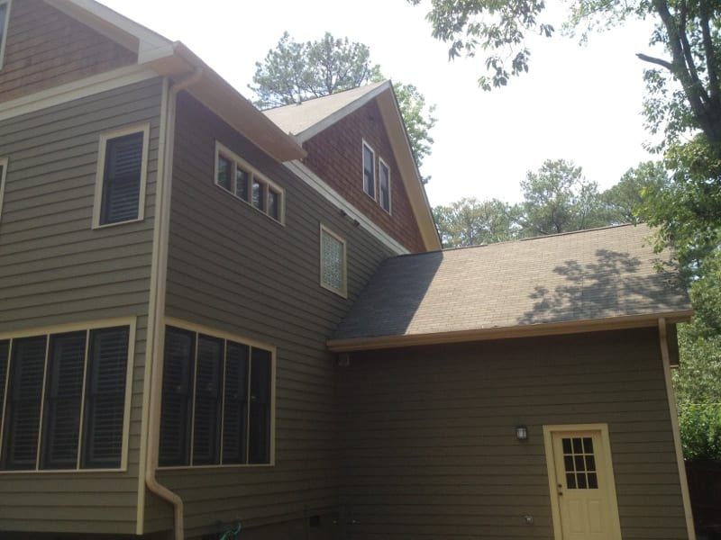 Olive sided house with a brick gable and a screened porch
