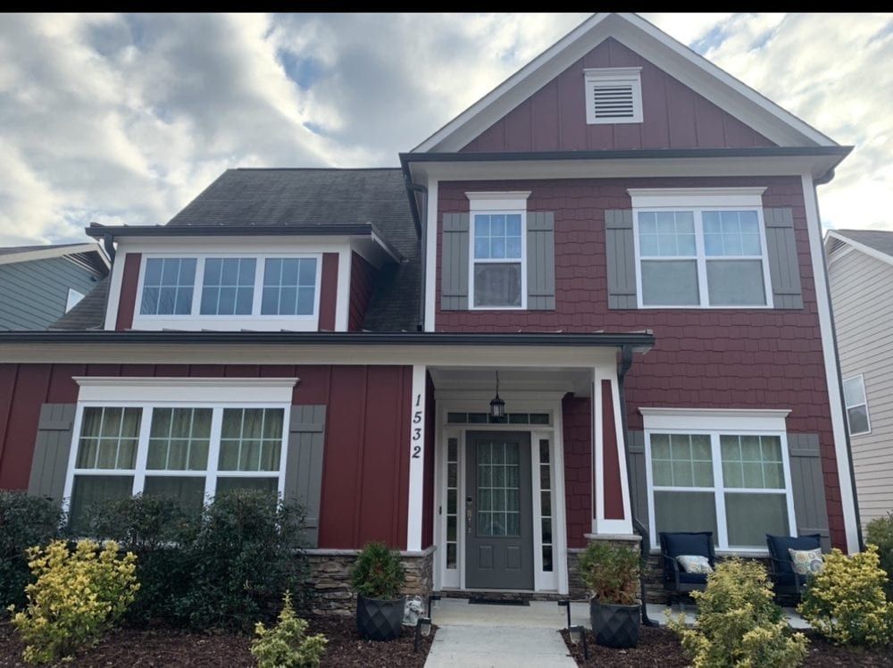 Two-story house with red siding, white trim, and a gray front door
