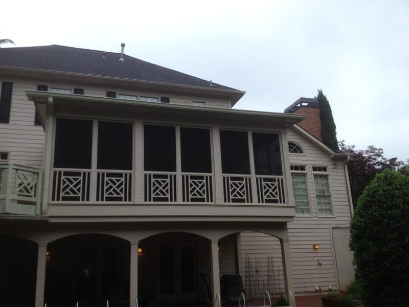 Screened upper porch with white lattice railings on a white sided house