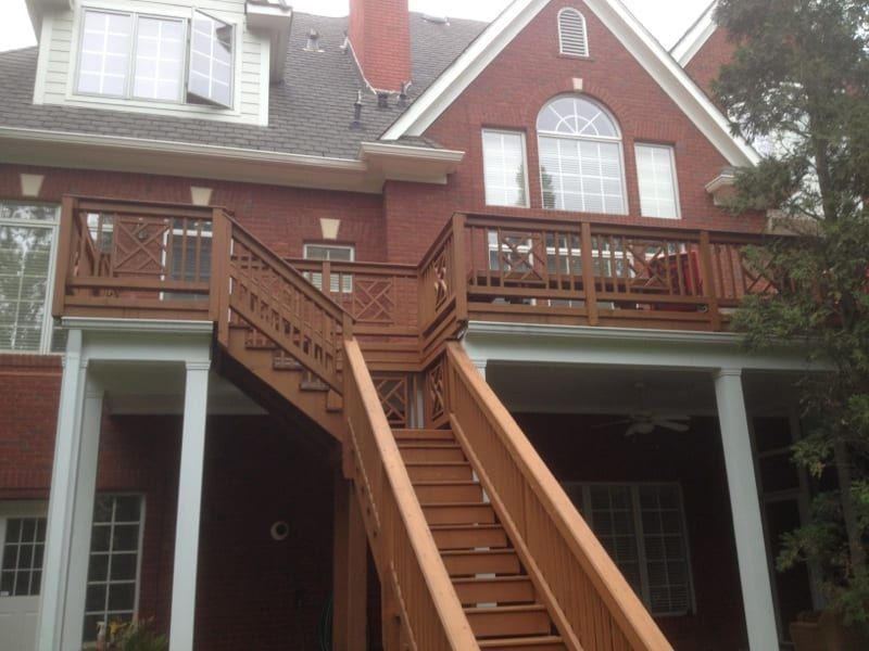 Stained wood staircase and deck on the back of a brick house