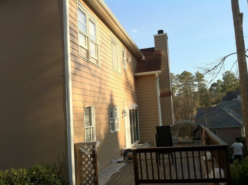 Side of a tan sided house with a wood deck and lattice below