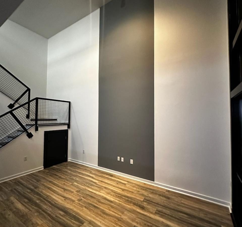 Two-story living room with white walls, a dark gray accent wall, and a black railing