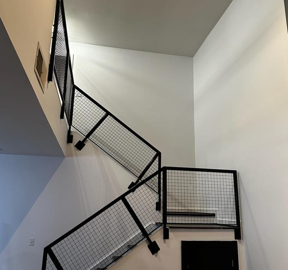 Black metal stair railing against freshly painted white walls