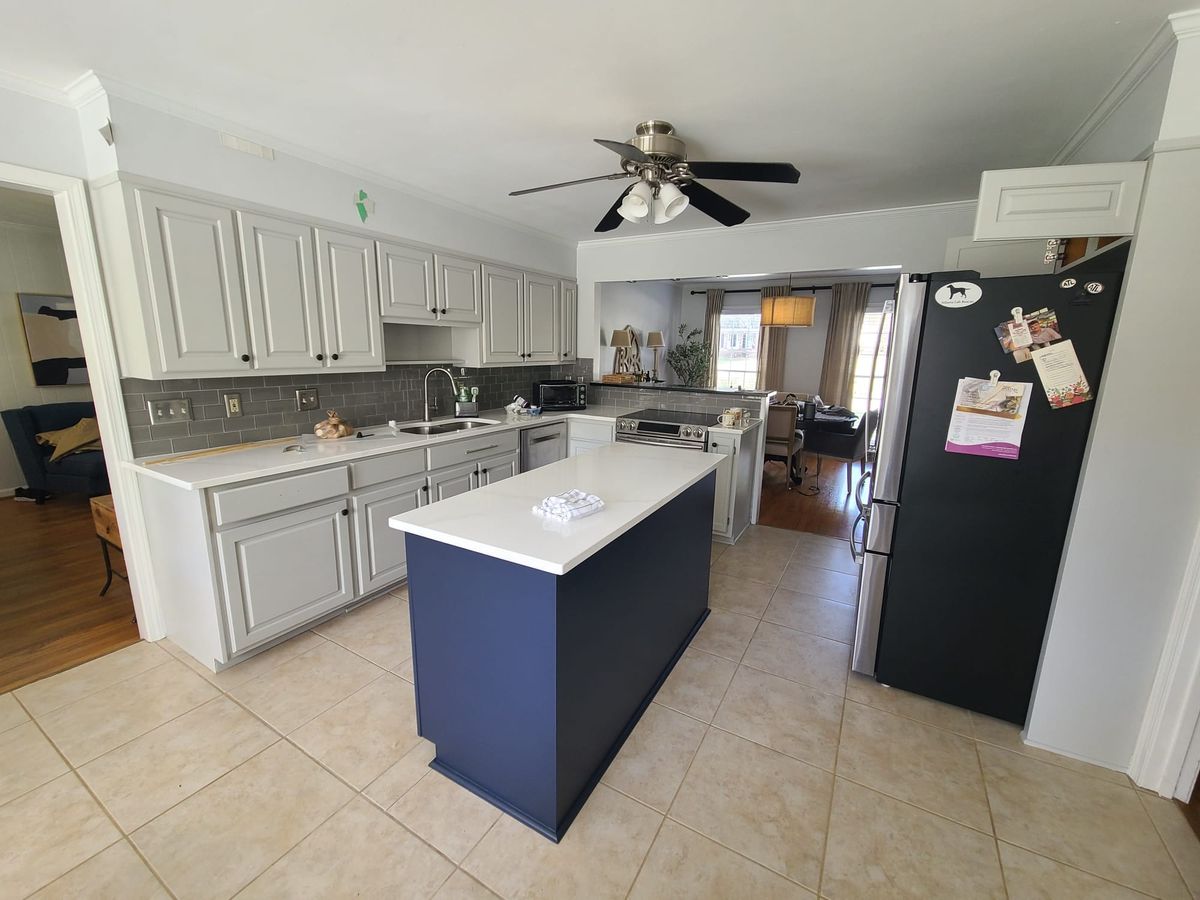 Finished kitchen with white cabinets, a navy island, and white counters