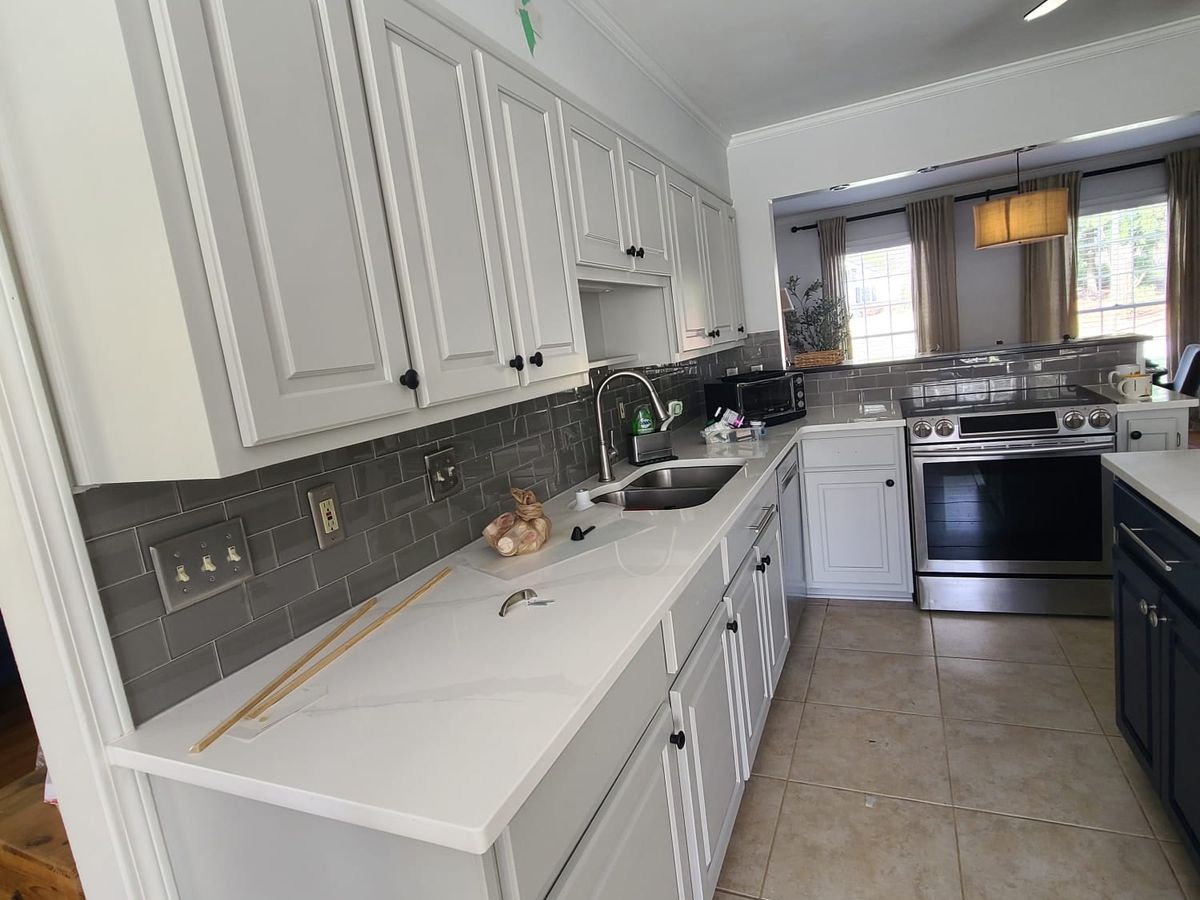 White cabinets and a gray tile backsplash along the finished kitchen wall