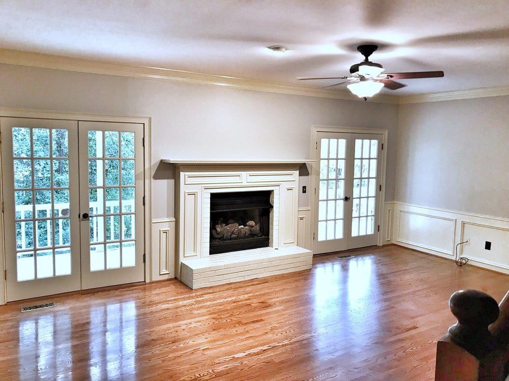 Living room with a white fireplace, French doors, and polished hardwood floors