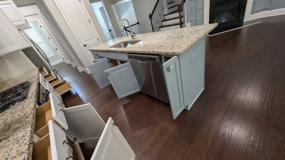 Kitchen with a gray island, granite counters, and cabinet doors and drawers open
