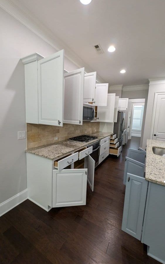 Narrow view of white upper cabinets and gray lower cabinets beside the range