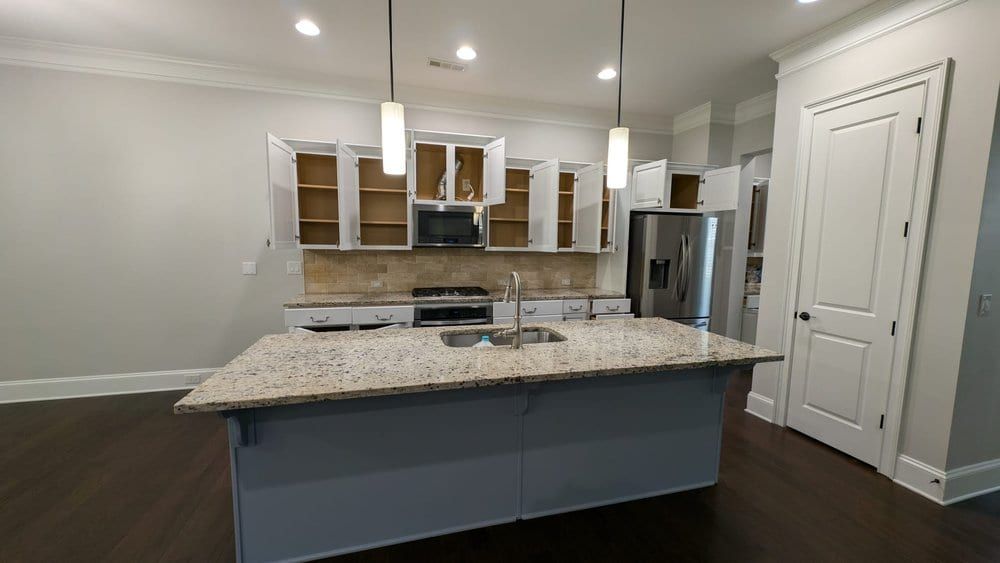 Kitchen with white cabinets and a gray island under pendant lights