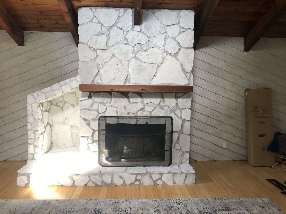 White-painted stone fireplace with a wood mantel under a beamed ceiling
