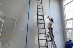Accent wall painting preparation, covering, and drywall repairs in a two-story Living Room by The Painting Group and Renovation