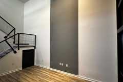 Bright and inviting living room with hardwood floors and stairs by The Painting Group and Renovation